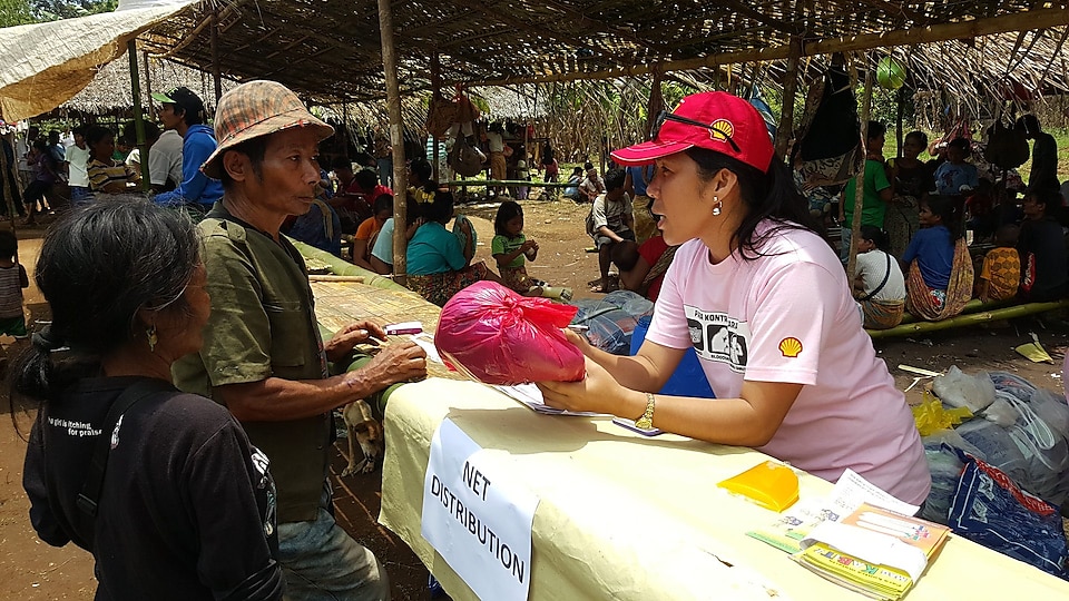 A volunteer distributing long-lasting insecticide-treated nets to locals