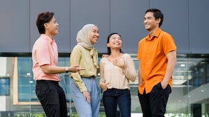 A group of employees are standing and having a casual chat and laughing