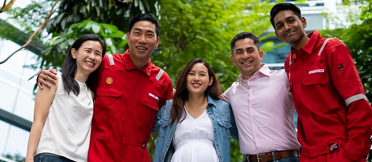 A group of five people standing closely together outdoors