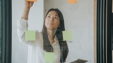 A woman placing post its on a glass wall