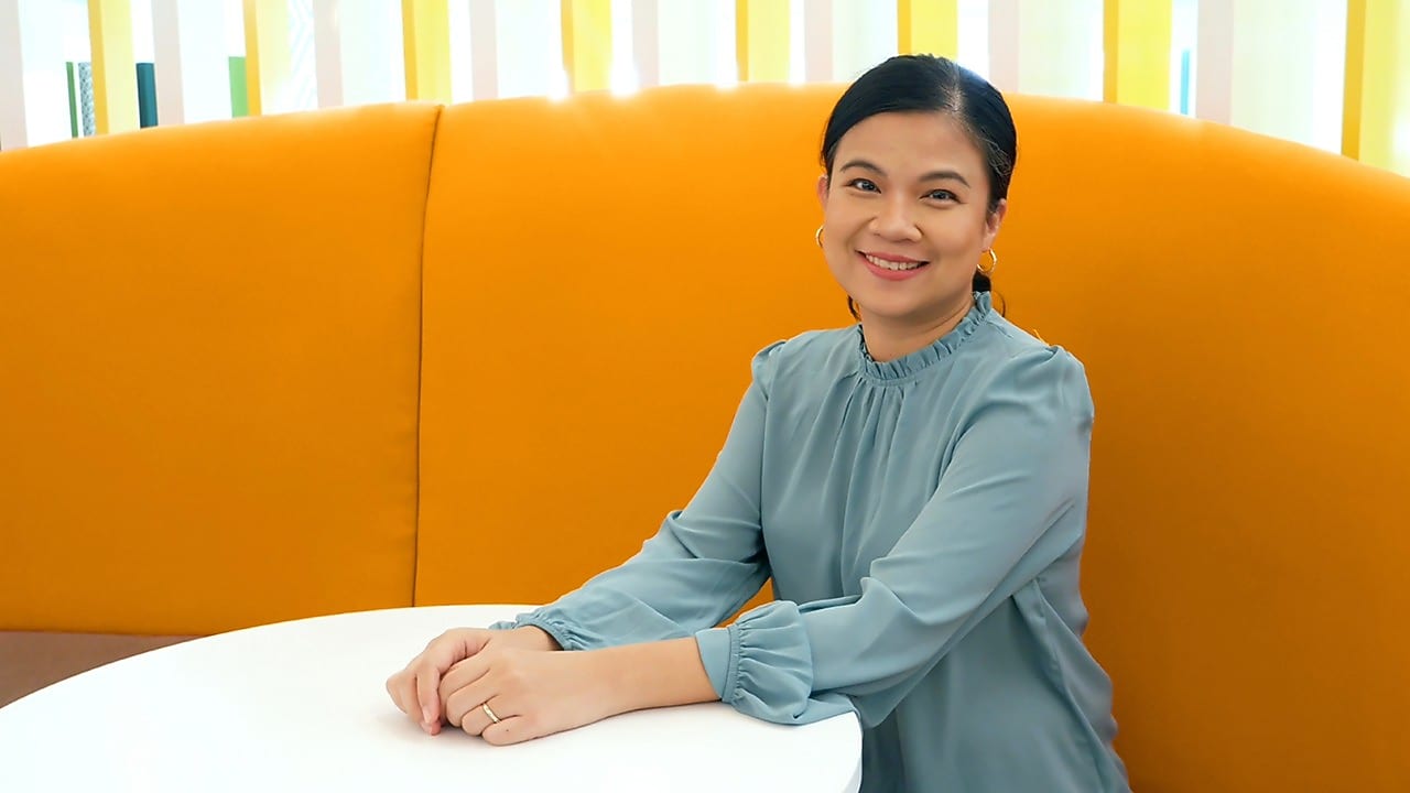A woman seated at a table in an orange office setting