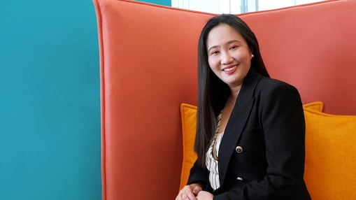 A woman sitting on an orange couch located in an office space