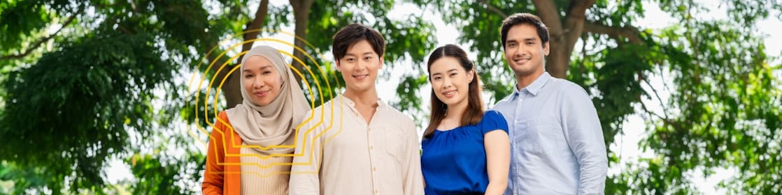 Four individuals standing outdoors with green trees in the background