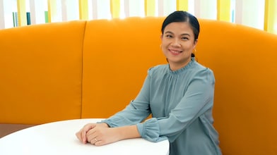 A woman seated at a table in an orange office setting