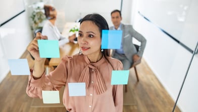 A woman placing post its on a glass wall