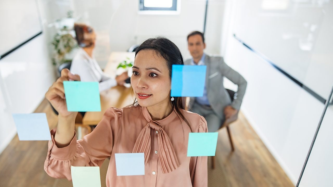 A woman looking at post it notes on a glass wall