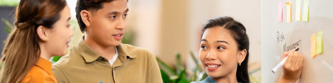 Team collaborating on strategy in office, with whiteboard and sticky notes