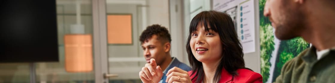 People seated at a conference table with laptops, discussing data shown on charts and graphs in a meeting room.