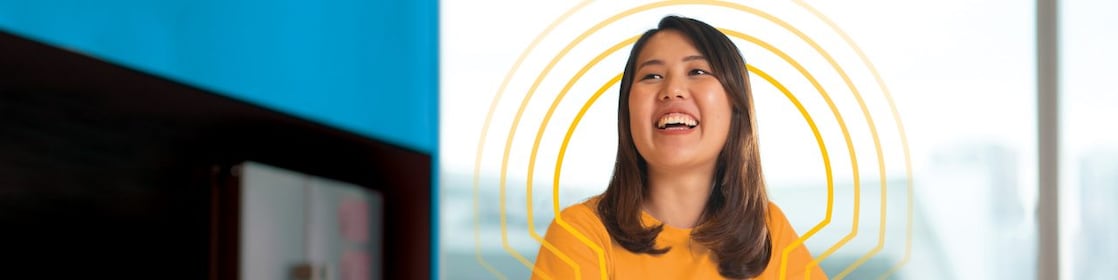 A female employee standing near a large coffee table at work and laughing