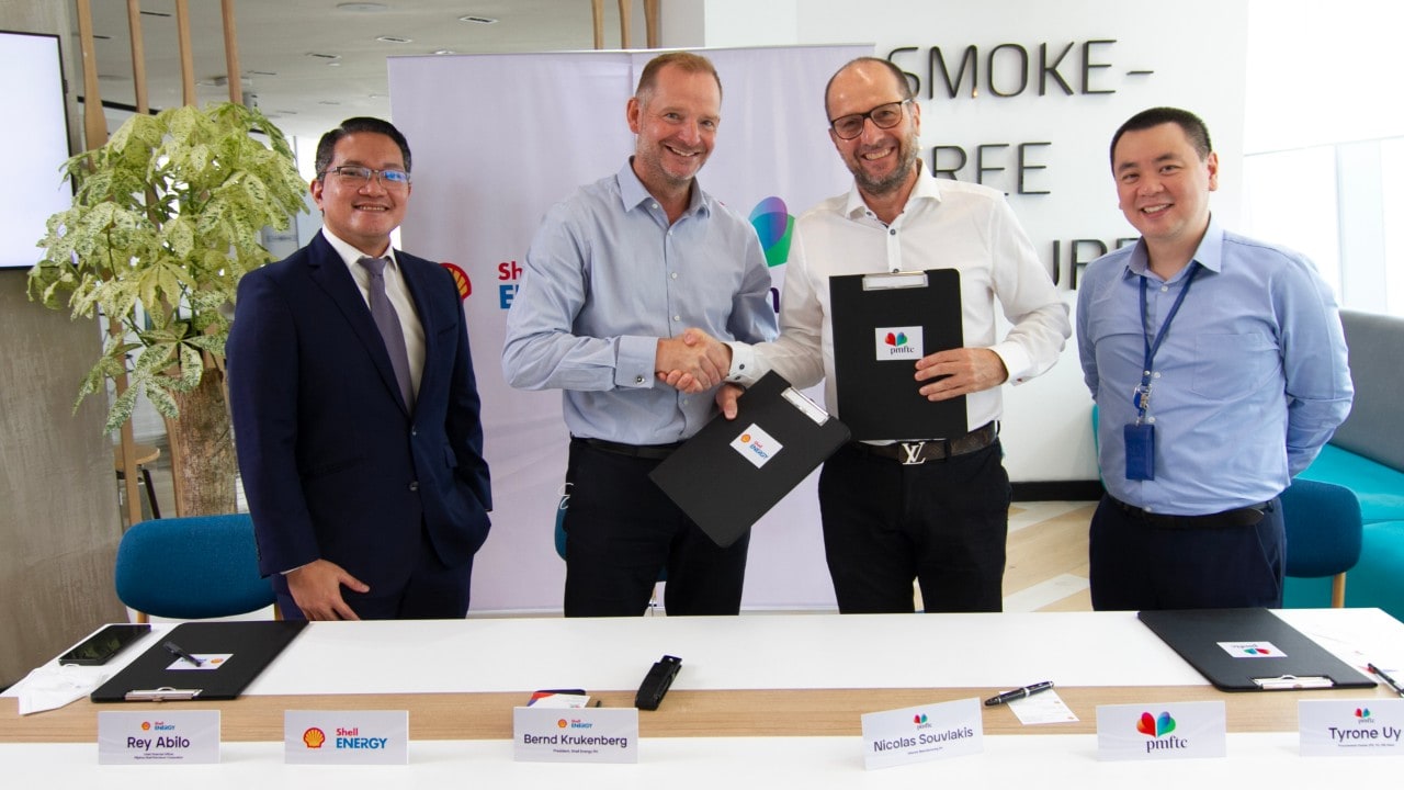 Two people shaking hands and other two people are standing