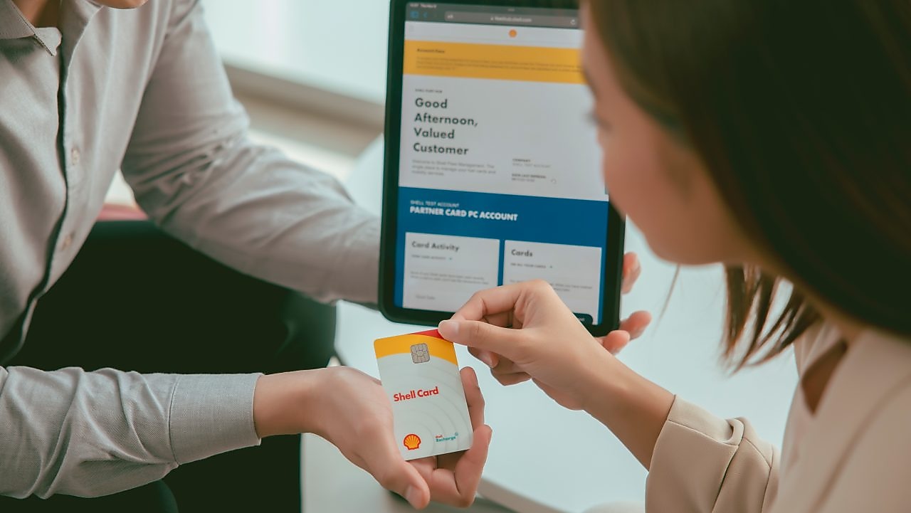 Shell customer holding a Shell card at an electric vehicle charging post