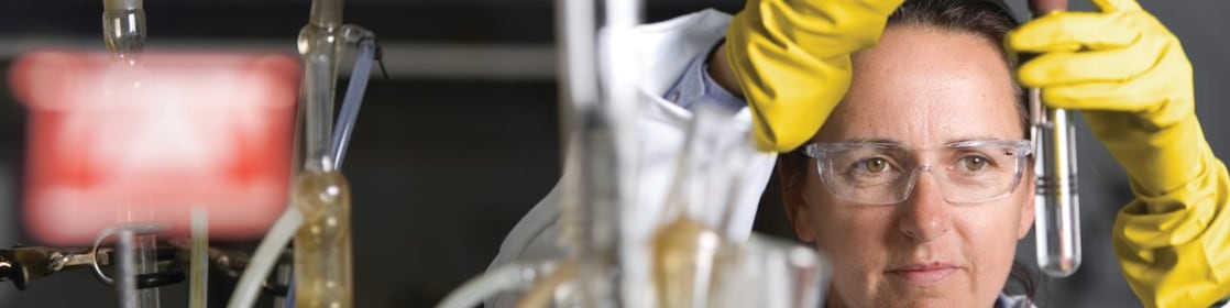 lady in safety goggles conducting a lab experiment