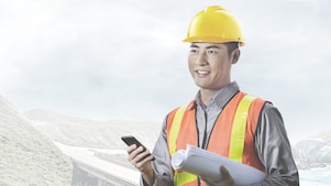 man wearing a yellow safety helmet holding a phone