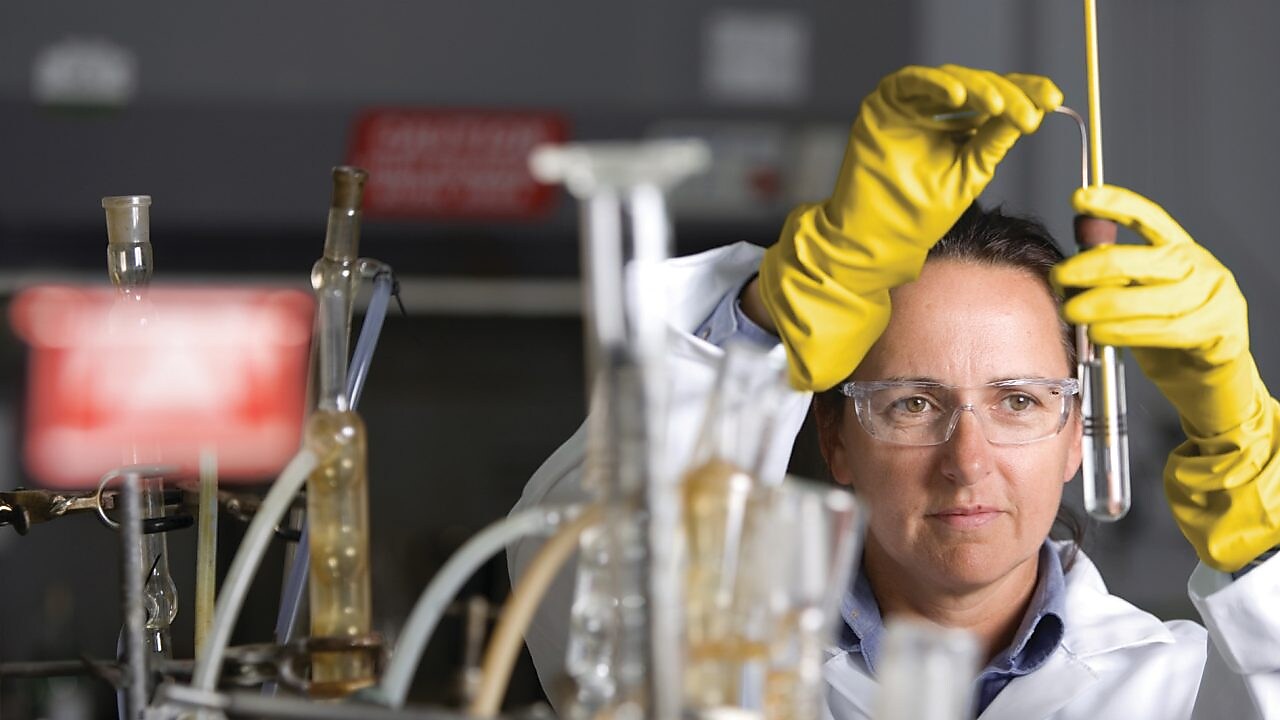lady in safety goggles conducting a lab experiment