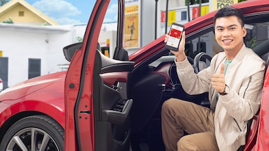 Man showing Shell App in his red car