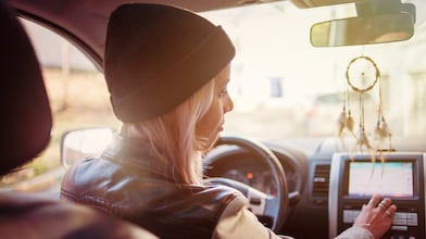 A young woman checks the instructions displayed on her car's built in navigation screen