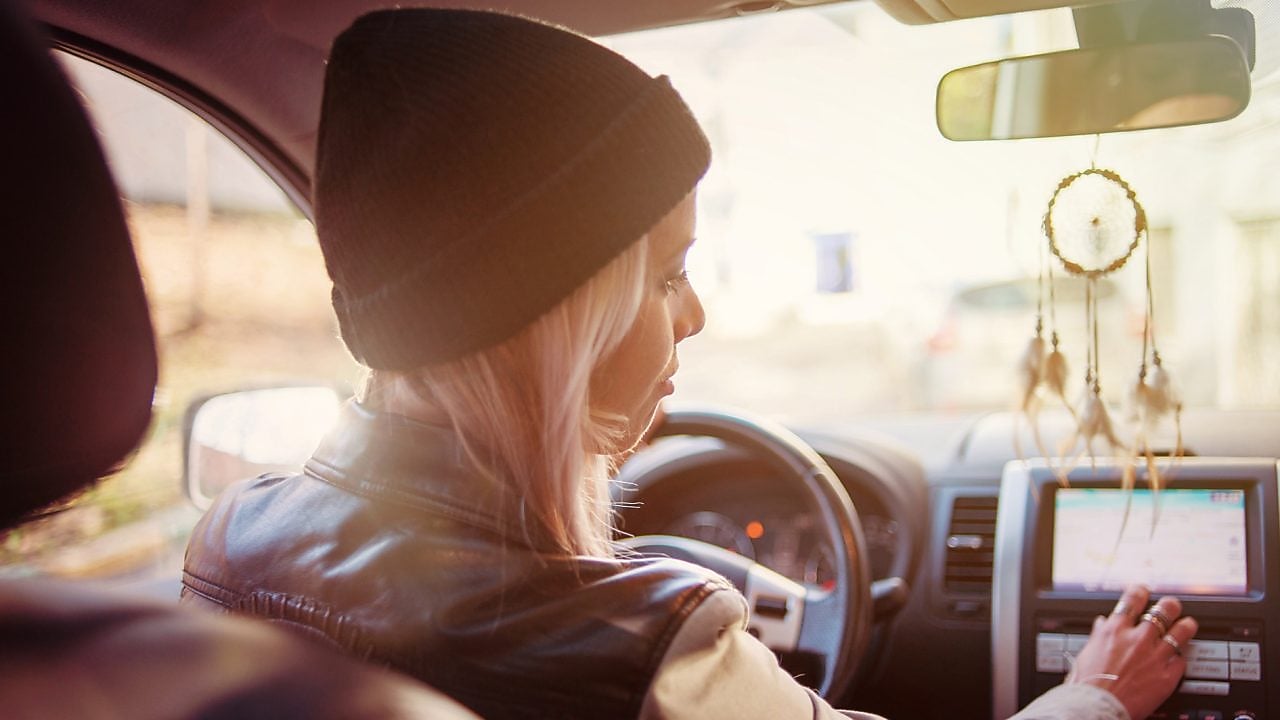 A young woman checks the instructions displayed on her car's built-in navigation screen