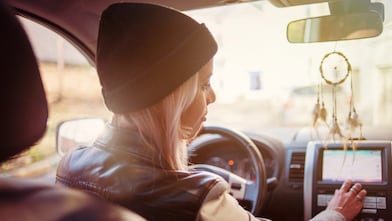 A young woman checks the instructions displayed on her car's built-in navigation screen