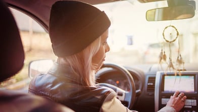 A young woman checks the instructions displayed on her car's built-in navigation screen