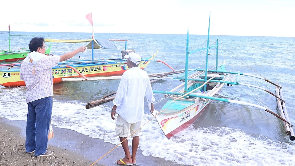 A priest blessing the boats of the fishermen beneficiaries  alt-text: A priest blessing boats of beneficiaires